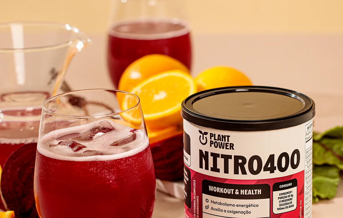 Lata de Nitro400 Beterraba e Laranja ao lado de um copo do suco pronto.
